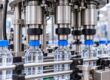 “Bottle capping machine applying caps to bottles on a conveyor” — use only if the photograph shows this.